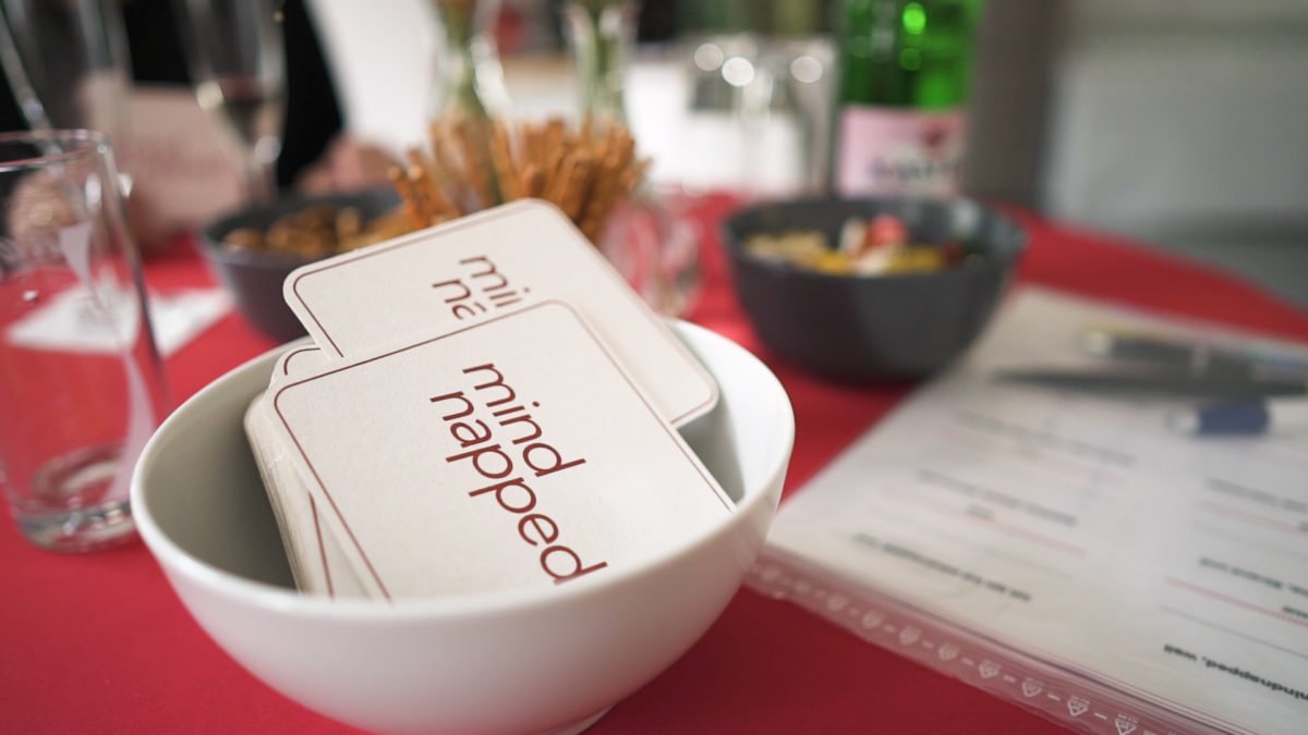 Bierdeckel in einer Schüssel neben Gläsern und Snacks
