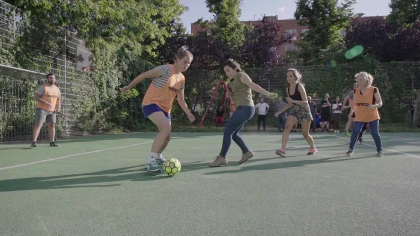 Junge Mädchen spielen Fussball auf Kunstrasen